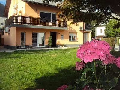 a house with pink flowers in the yard at Apartment Japka in Bovec