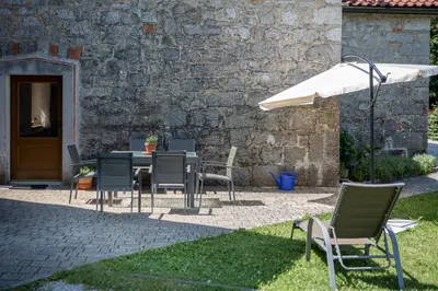 a patio with a table and chairs and an umbrella at Villa Anton - The Old Dairy in Hrušica