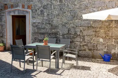 a table and chairs and an umbrella on a patio at Villa Anton - The Old Dairy in Hrušica