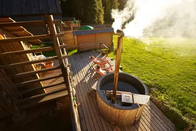 a hot tub sitting on a wooden deck next to a field at Alp Glamping Village in Radovljica