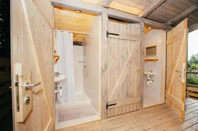a bathroom with a wooden door and a shower at Alp Glamping Village in Radovljica
