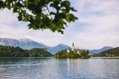 a church on an island in the middle of a lake at Alp Glamping Village in Radovljica