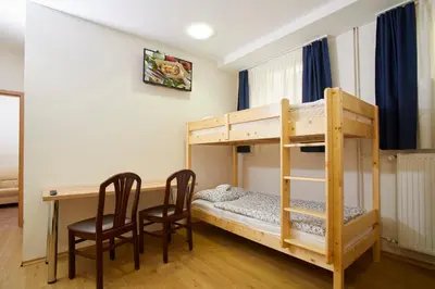 a room with a bunk bed and a desk and chairs at Hostel Delalut in Ravne na Koroškem