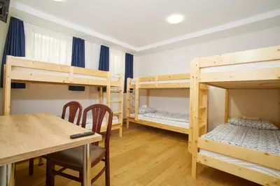 a room with four bunk beds and a table at Hostel Delalut in Ravne na Koroškem