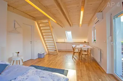 a room with a bed and a table and a staircase at Apartments Perla in Zgornje Gorje