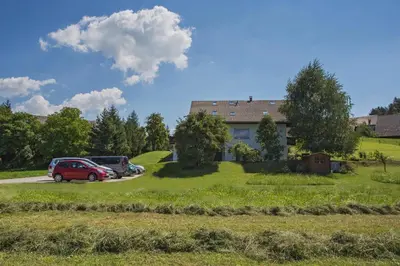 a house with cars parked in a parking lot at Apartments Perla in Zgornje Gorje