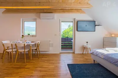 a dining room with a table and chairs and a bed at Apartments Perla in Zgornje Gorje