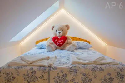 a teddy bear sitting on a bed holding a heart at Apartments Perla in Zgornje Gorje