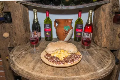 a table with a plate of food and two glasses of wine at Vineyard Cottage Rataj 2 in Novo Mesto