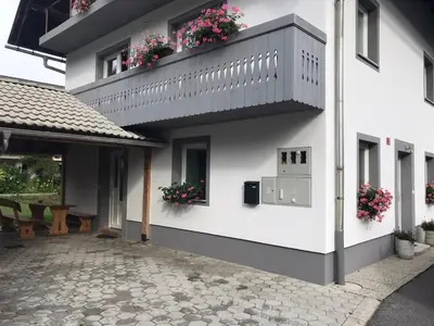 a white building with flower boxes and a balcony at Apartma Tajč in Bohinj