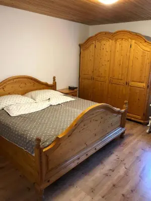 a bedroom with a wooden bed and a wooden cabinet at Holiday house Pr Robč in Bovec
