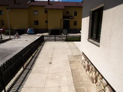 a walkway next to a building with a person riding a bike at Apartments Otašević in Kranjska Gora