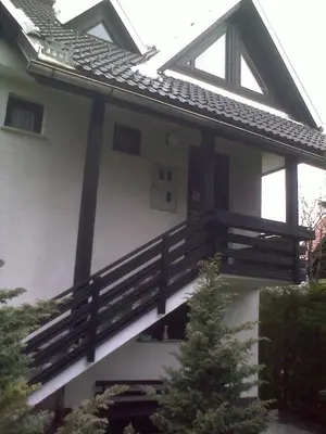 a house with a porch with a wooden balcony at Apartments Otašević in Kranjska Gora