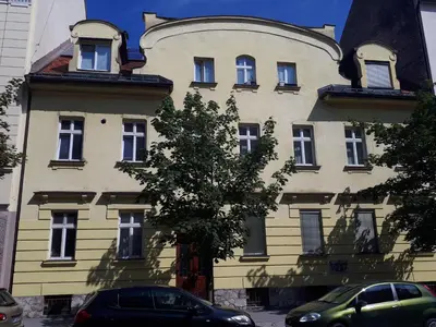 a yellow building with a tree in front of it at Tabor - Apartments Rozmanova Street in Ljubljana