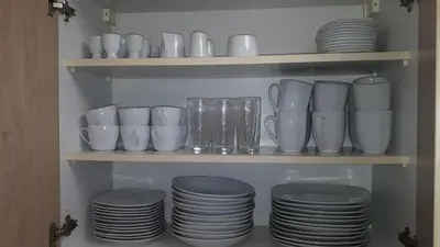 a bunch of white cups and plates on a shelf at Tabor - Apartments Rozmanova Street in Ljubljana