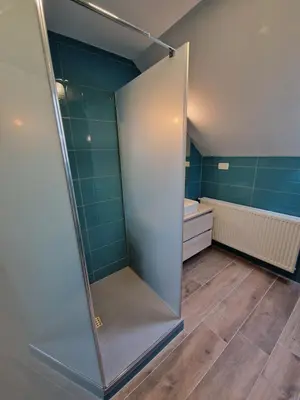 a shower stall in a bathroom with green tiles at Apartment Ravnik Brod 13 in Bohinj