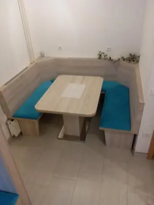 a wooden table and bench in a room with blue cushions at Apartment Ravnik Brod 13 in Bohinj