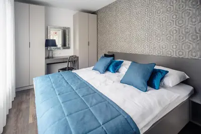a bedroom with a large bed with blue pillows at Apartments Villa Tatiana in Bled