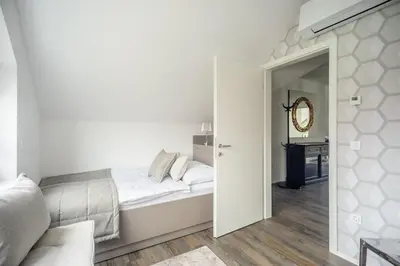 a white bedroom with a bed and a mirror at Apartments Villa Tatiana in Bled