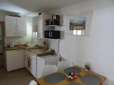 a kitchen with white cabinets and a table and a table and chairs at Apartment Tjaša in Radovljica