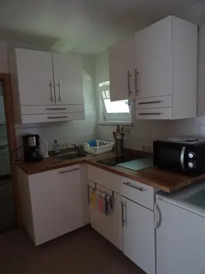a kitchen with white cabinets and a black microwave at Apartment Tjaša in Radovljica