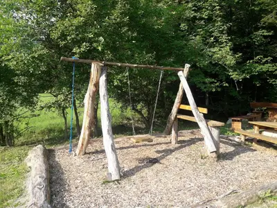 a swing set in a park with a bench at Simnovi apartmaji - surrounded by nature in Kamnik