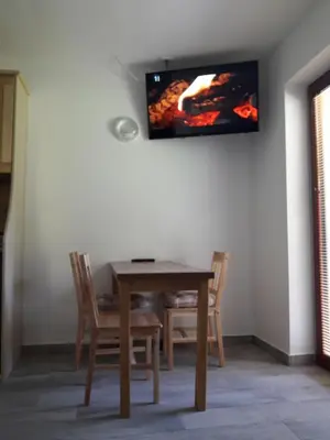 a dining room table with chairs and a tv on the wall at Simnovi apartmaji - surrounded by nature in Kamnik