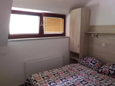 a small bedroom with a bed and a window at Simnovi apartmaji - surrounded by nature in Kamnik