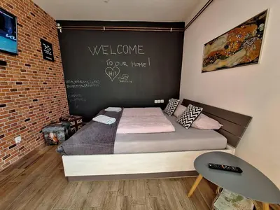 a bedroom with a bed with a welcome sign on the wall at Apartment GREEN&URBAN in Celje
