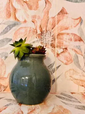 a green vase with flowers in it sitting on a table at Enam Room in Kojsko