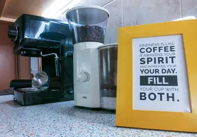 a sign on a counter next to a coffee maker at Goldenfields apartment in Kranj