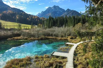 a bench next to a river with mountains in the background at Goldenfields apartment in Kranj