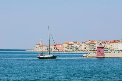 a sail boat in the water with a lighthouse at Goldenfields apartment in Kranj