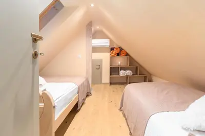 a attic bedroom with two beds and a staircase at Bohinj Cottage Pr' Maricki - house in nature with hot tub & sauna in Bohinj
