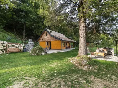 a wooden cabin in a yard with a tree at Bohinj Cottage Pr' Maricki - house in nature with hot tub & sauna in Bohinj
