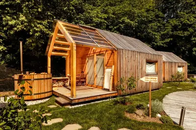 a small wooden cabin with a deck in a yard at Glamping Mountain Fairy Tale in Bistrica pri Tržiču