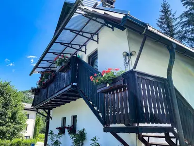 a house with a balcony with flowers on it at Apartment Ticar in Bohinj