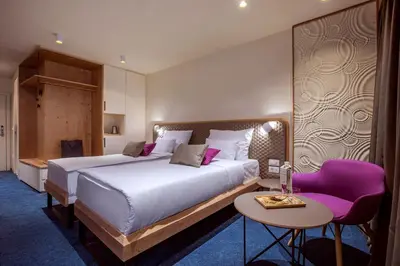 a bedroom with a large bed and a purple chair at Hotel Park - Sava Hotels & Resorts in Bled