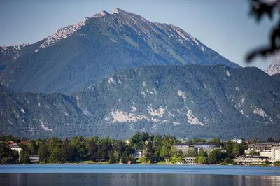a mountain with a town in front of a body of water at Hotel Park - Sava Hotels & Resorts in Bled