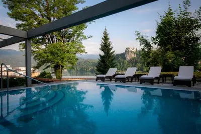 a swimming pool with chairs and a view of the mountains at Rikli Balance Hotel – Sava Hotels & Resorts in Bled