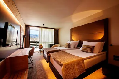 a hotel room with two beds and a large window at Rikli Balance Hotel – Sava Hotels & Resorts in Bled