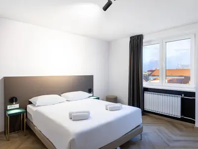 a bedroom with a large white bed and a window at B&B HOTEL Maribor Orel in Maribor