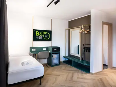 a bedroom with a bed and a desk and a mirror at B&B HOTEL Maribor Orel in Maribor
