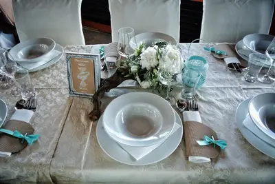 a table with a white table cloth with a plate and flowers at Hotel Grosuplje in Grosuplje