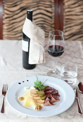 a plate of food and a bottle of wine on a table at Hotel Grosuplje in Grosuplje