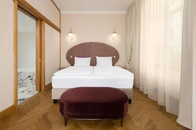 a bedroom with a white bed and a chair at Grand Hotel Union Eurostars in Ljubljana
