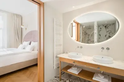 a bathroom with a bed and two sinks and a mirror at Grand Hotel Union Eurostars in Ljubljana