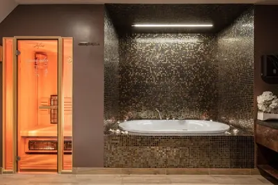 a bathroom with a tub with a tiled wall at Eurostars uHOTEL in Ljubljana