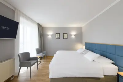 a hotel room with a large bed and chairs at Eurostars uHOTEL in Ljubljana