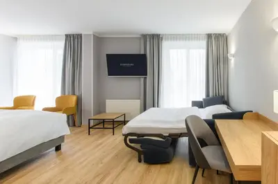a hotel room with two beds and a table and chairs at Eurostars uHOTEL in Ljubljana